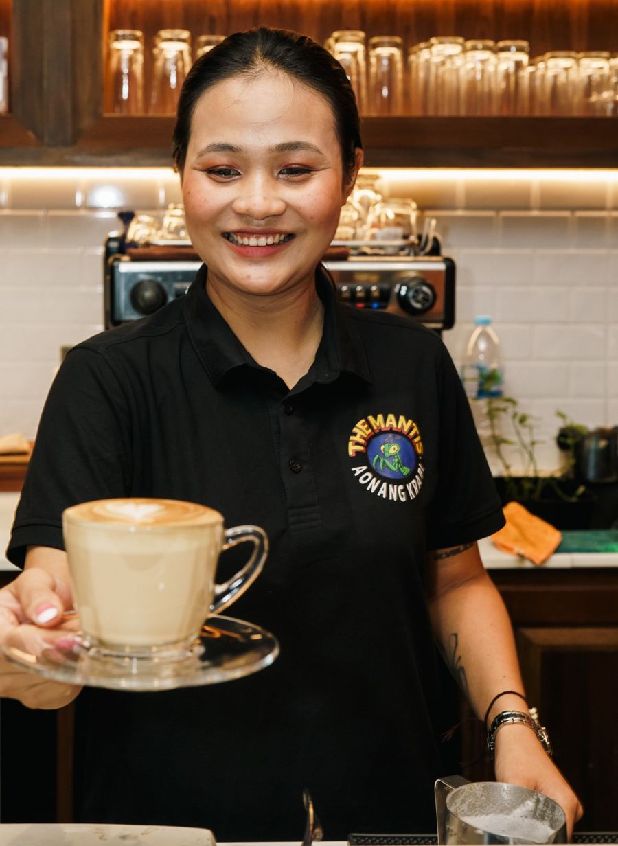 Smiling barista Susan holding a fresh latte at the coffee bar